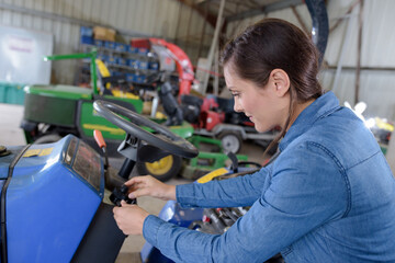 female mechanic working on lawnmower in workshop