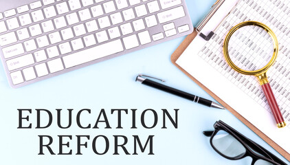 EDUCATION REFORM text on blue background with keyboard and clipboard, business concept