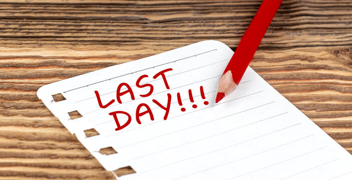 Word LAST DAY on a paper with ped pencil on wooden background