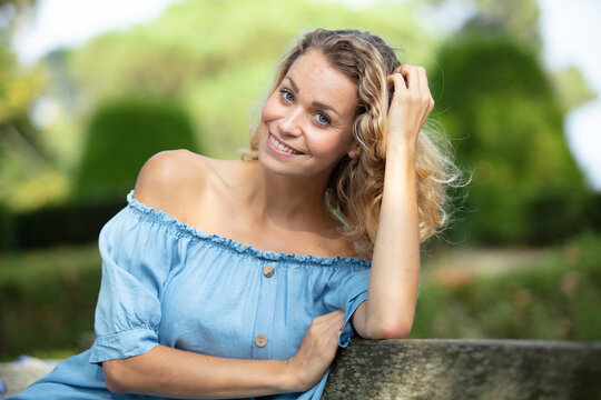 blond smiling woman sitting on park bench