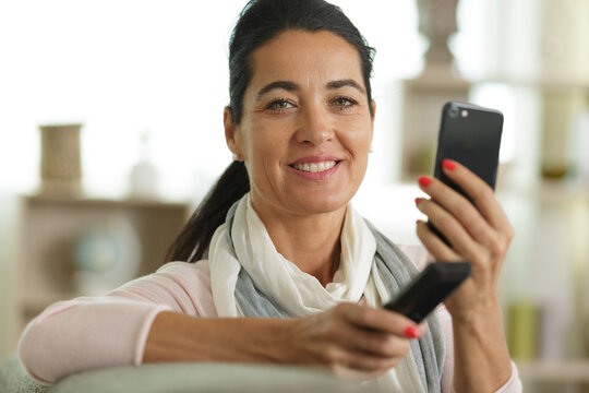 woman smiling with cellphone in hands sitting on sofa
