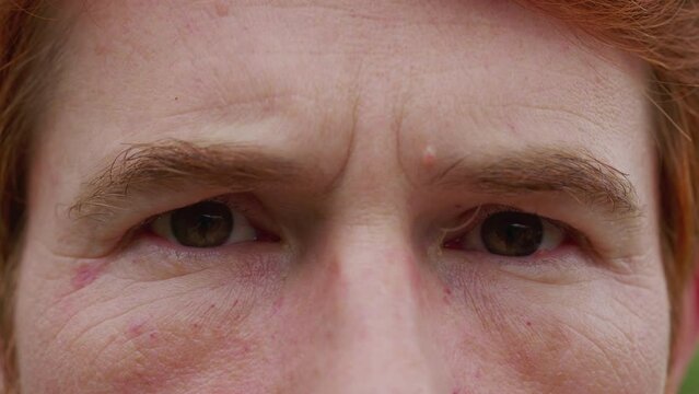 Man with serious judgemental emotion macro close-up eyes. A male person frowning looking at camera feeling angry and upset
