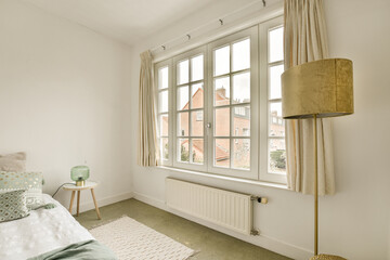 a bedroom with a bed and a lamp on the window sid in it's corner, next to a small table