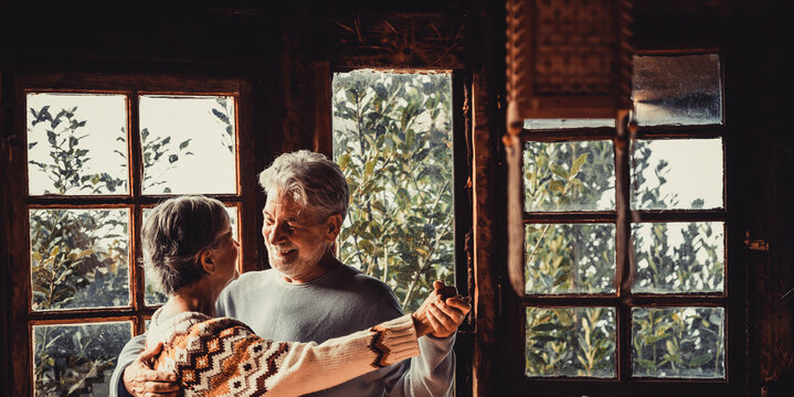 Romantic Youthful Couple Of Retired Senior People Dancing Together At Home In Indoor Happy Love Leisure Activity. Togetherness Relationship Mature Man And Woman Dance And Look On Eyes. Chalet Vacation