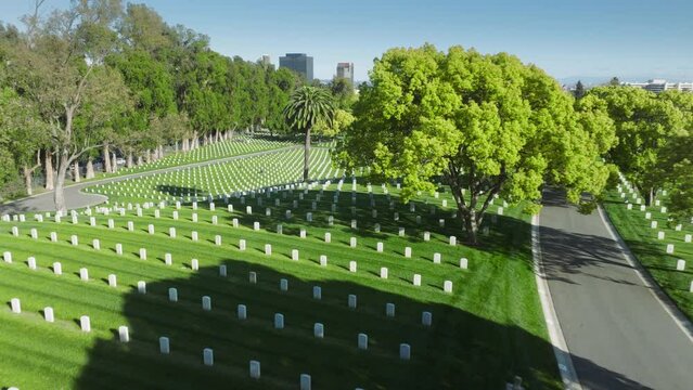 Aerial Los Angeles National Cemetery California USA. Drone flying above scenic green field with straight rows white grave plates on summer day. National cemetery where buried all members armed forces
