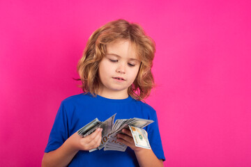 Cash money in dollar banknotes. Child with money dollar bills, standing dreamy of rich against isolated studio background.