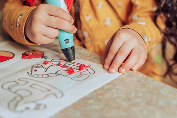Close-up of a little dark-haired girl drawing with a 3d pen in a classroom.STEM-education,hobby,technology concept.