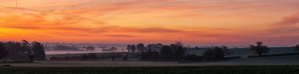 Panorama view of View of English countryside on a misty morning at dawn 