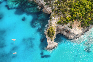 Summer holiday background. Top view of seascape with beautiful stone cliff and clear blue water on a sunny summer day. Sea coast, aerial drone shot. Travel concept