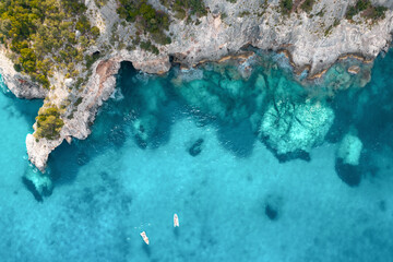 Summer holiday background. Top view of seascape with beautiful stone cliff and clear blue water on a sunny summer day. Sea coast, aerial drone shot. Travel concept