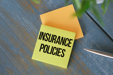 Insurance Policies text on sticker with pen on the Wooden background