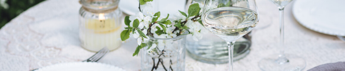 Rustic zero waste wedding decor with natural elements. Fresh spring blooming flowers, candles, linen napkins, wine glasses. Eco friendly decoration for special holiday dinner. Romantic place banner