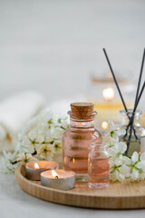 Aromatherapy, home decor concept. Glass perfume bottle, elegant composition with spring flowers. Burning candles, spa setting, essential oils, organic pure aromatic ingredients, atmosphere of relax