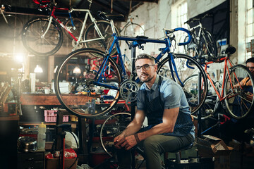 Portrait, wrench and serious repair man in bicycle shop, store or cycling workshop. Face, bike mechanic and male person, business owner or mature professional technician with glasses and confidence.
