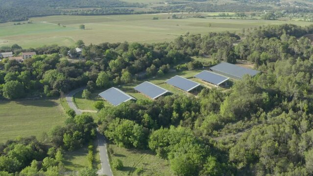 Aerial shot approaching a solar panel farm nestled in a forest in the countryside