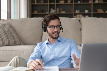Successful handsome young adult student man in headphones attending online educating seminar,...