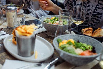 Different dishes laid out on table in cafe. Group of friends spend time in restaurant. Leisure in cafe with mates. 