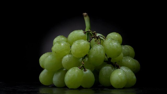 Big bunch grapes with drops of water on a black background. Rotation