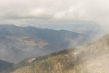 Fototapeta premium Ascent to Pastukhova Mountain on Arkhyz. Snow-capped mountains with low clouds