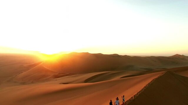 Travel, desert and silhouette of people at sunset for destination, freedom or summer trip. Footprints, adventure and journey with friends on horizon of sand dunes for abroad trip on Namibia vacation