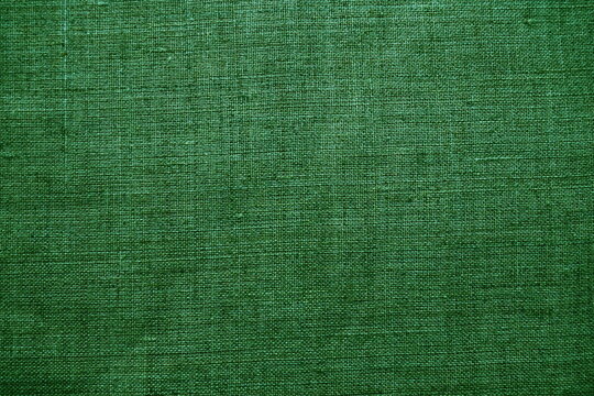 Fabric texture background. Green fabric with weave. Natural slightly wrinkled look of the material. Uniform copy space background. Cotton, canvas or woolen thin fabric laid evenly on the surface.