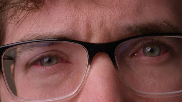 man puts on glasses with both eyes infected with pink eye - close up on face