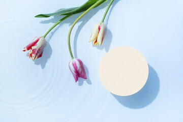 Podium or pedestal with water ripple and tulips flat lay, top view. Cosmetic template, copy space