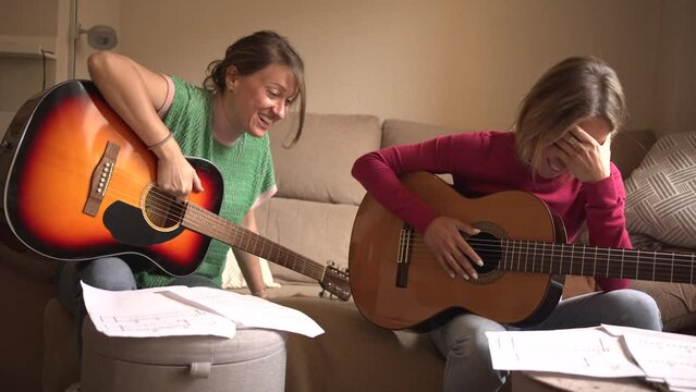friends practising guitar in a canteen laughing out loud at not playing well, having fun learning to play the instrument