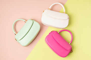 Three pastel colored womens hand bags on pink background. Summer fashion concept