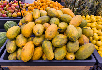 Tropical fruits on display in supermarket. Papayas, lemons, mangos, watermelons, pineapples. 
