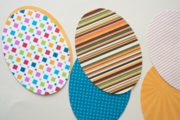 layered whimsical ovoid shapes cut from scrapbook paper using a machine arranged on beige