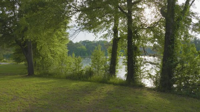 footage of a gorgeous spring landscape at Proctor Landing Park at sunset with rippling water surrounded by lush green trees and plants at Lake Acworth in Acworth Georgia USA