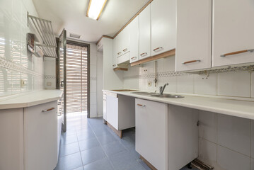 Fototapeta na wymiar A simple kitchen with white furniture and countertops of the same color with wood-colored details