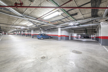 A few parking spaces of a large garage in an urban residential apartment building with white