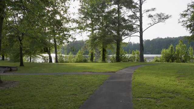 footage of a gorgeous spring landscape at Proctor Landing Park at sunset with rippling water surrounded by lush green trees and plants and a pergola with benches at Lake Acworth in Acworth Georgia USA