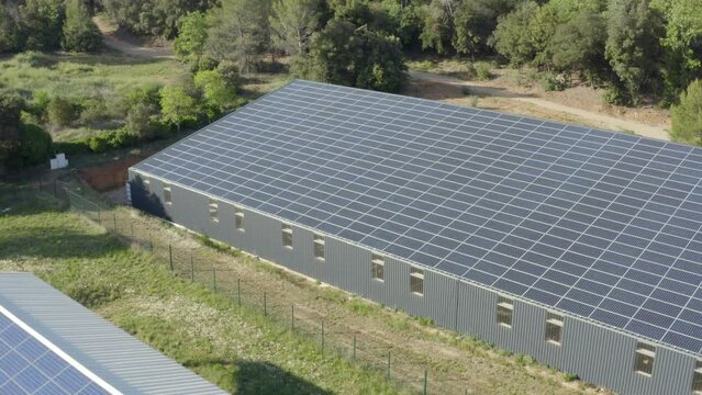Aerial shot of a shed and barns with solar panels on the roof in the forest