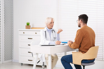 Doctor consulting patient at white table in clinic