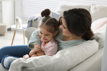 Obraz premium Young mother and her daughter spending time together on sofa at home