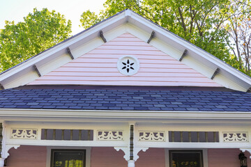 Details of a pink shotgun duplex with a gabled roof and decorative touches.