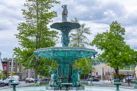 The Broadway Fountain in Madison, Indiana with spring trees, and clouds.