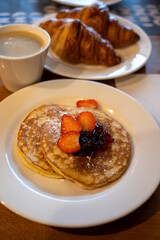 Breakfast with homemade American pancakes served with strawberry jam and fresh ripe strawberries and croissants