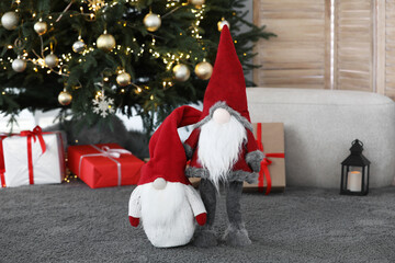 Obraz premium Cute Scandinavian gnomes on carpet near Christmas tree in room