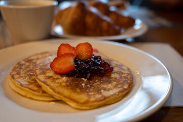 Breakfast with homemade American pancakes served with strawberry jam and fresh ripe strawberries and croissants