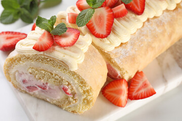 Delicious cake roll with strawberries and cream on white table, closeup