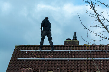 Installing of solar panels on roof in cloudy winter day, green energy in Europe