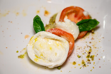Fresh vegetarian caprese salad, buffalo mozzarella cheese, red tomatoes, olive oil. Italian food served in restaurant, close up