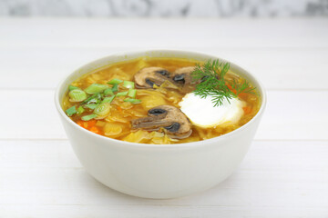 Delicious sauerkraut soup with mushrooms, green onion, dill and sour cream on white table