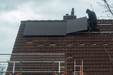 Installing of solar panels on roof in cloudy winter day, green energy in Europe