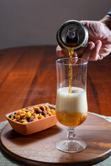 Pouring of German wheat beer is glass and bowl with party mix nuts