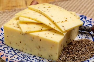 Cheese collection, piece of cow milk Dutch gouda cheese with dried aromatic cumin seeds close up